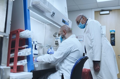 Infectious disease expert Dr. Drew Weissman looking over colleague's shoulder in lab